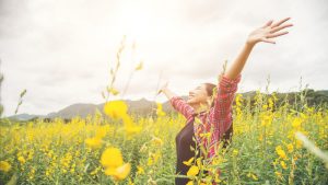 Young beautiful woman standing in the flower field enjoyment.